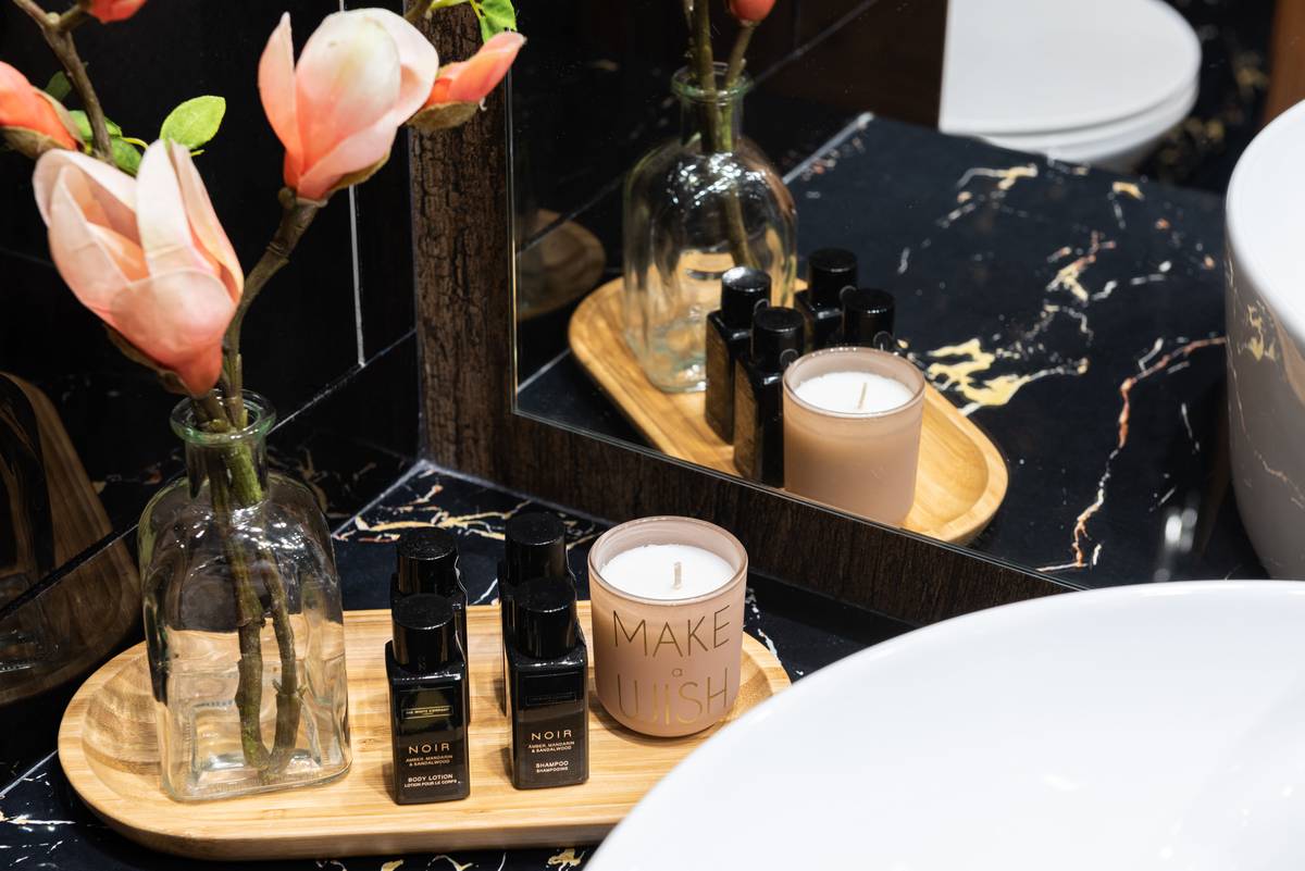 bathing essential bath oil body wash being poured into warm bathwater with floating botanicals